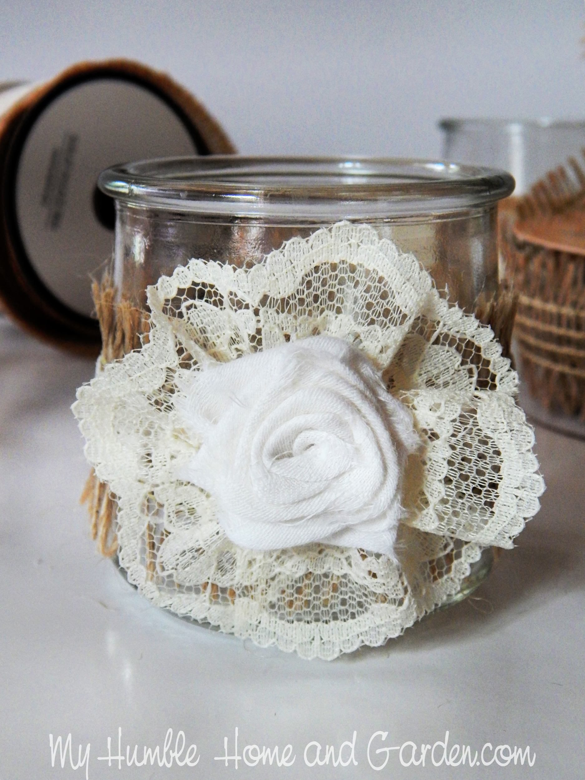 https://myhumblehomeandgarden.com/2021/07/12/shabby-chic-burlap-trim-yogurt-jars-easy-diy/glue-the-fabric-rose-on-top-of-the-lace-rosette/